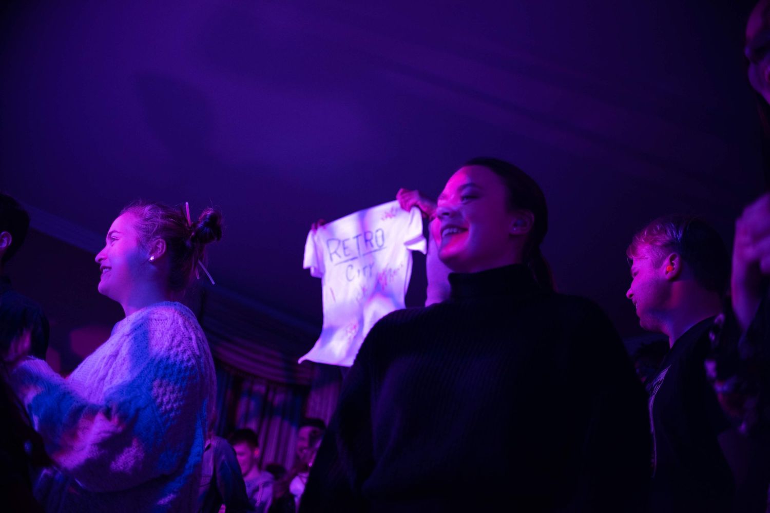 Concert crowd silhouettes illuminated by purple stage lighting.