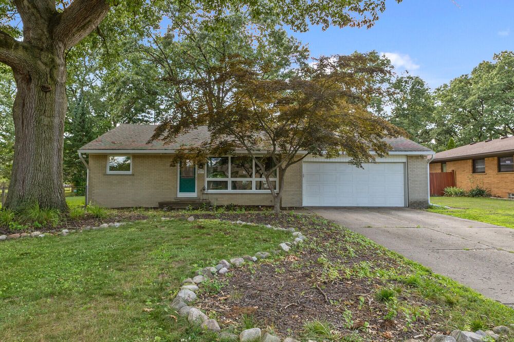 Charming ranch home with Japanese maple tree, white garage, teal front door, and landscaped yard.