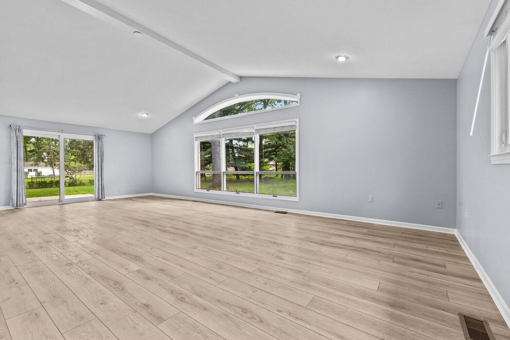 Bright room with vaulted ceilings, large sliding glass doors, recessed lighting, and wood floors.