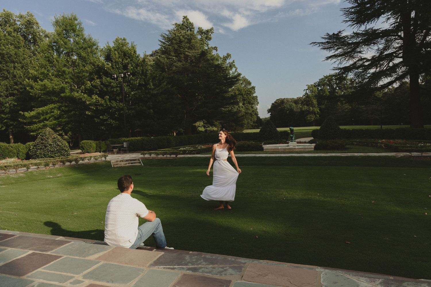Couple enjoying a relaxing moment on stone patio overlooking manicured garden.