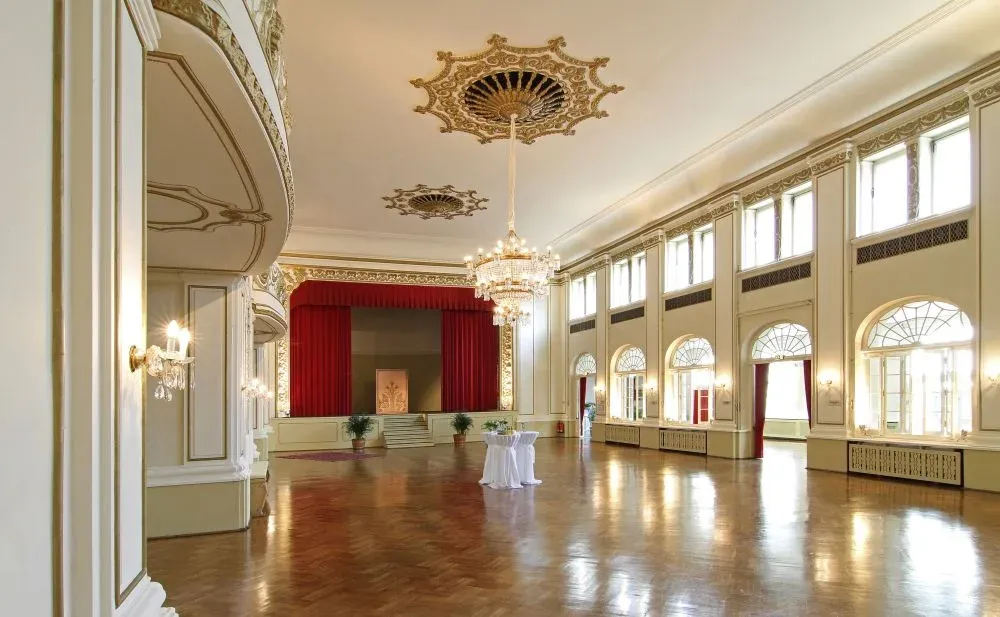 Elegant white ballroom interior with crystal chandeliers, high ceilings and polished wood floors. Organized wedding by MyCastleWedding.