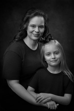 Black and white portrait series showing tender moments between parent and child in matching dark clothing.