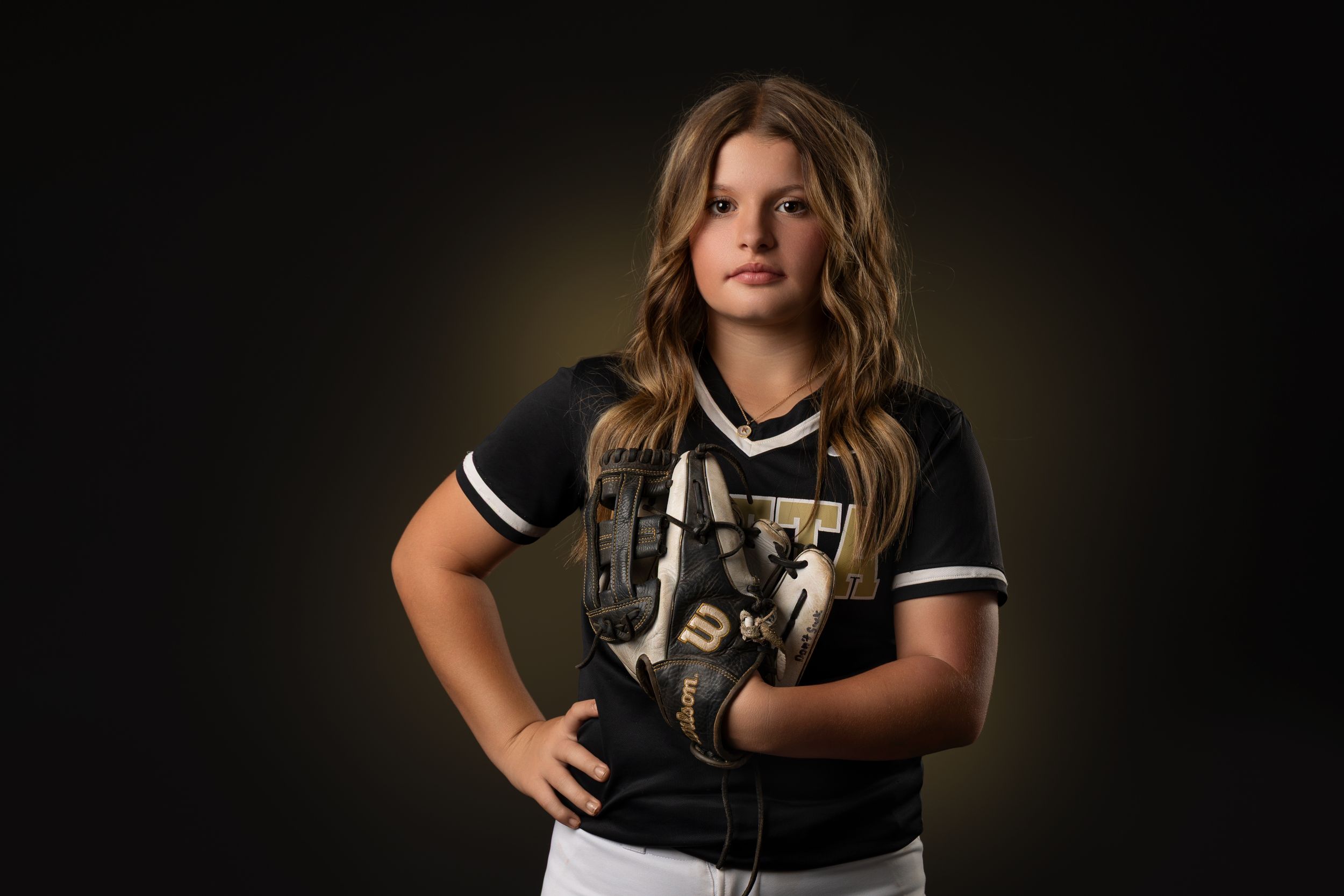 Athletic figure in black and white striped jersey holding softball bat in professional studio lighting setup.