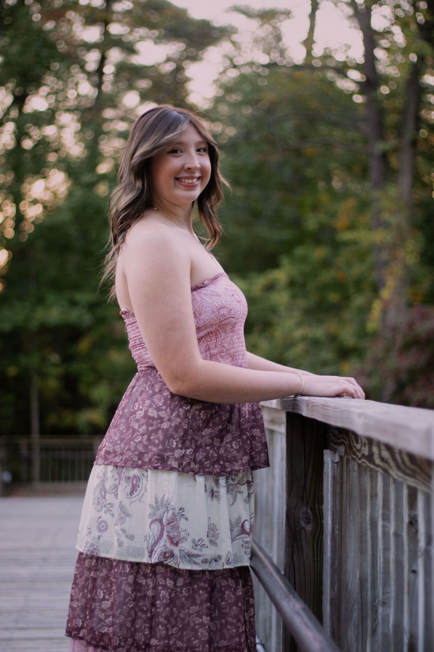 Young woman naturally laughing outside with a pond and bridge in the background.