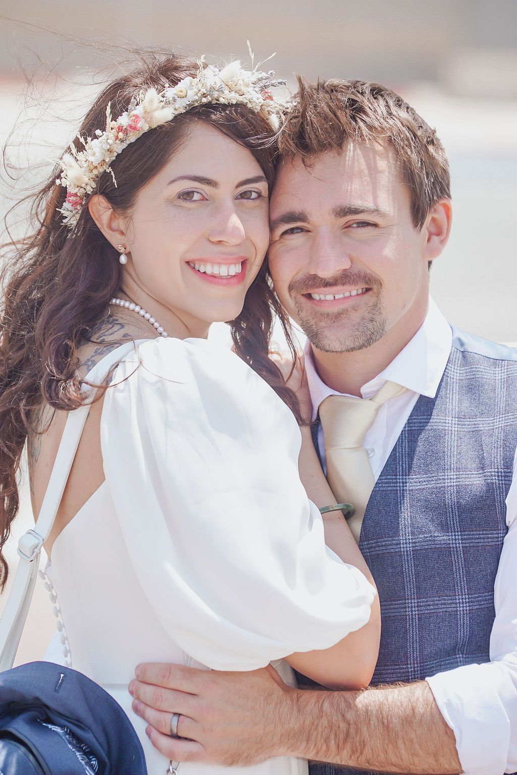 Bride and groom cuddle on the runway of Gibraltar airport, smiling at the camera