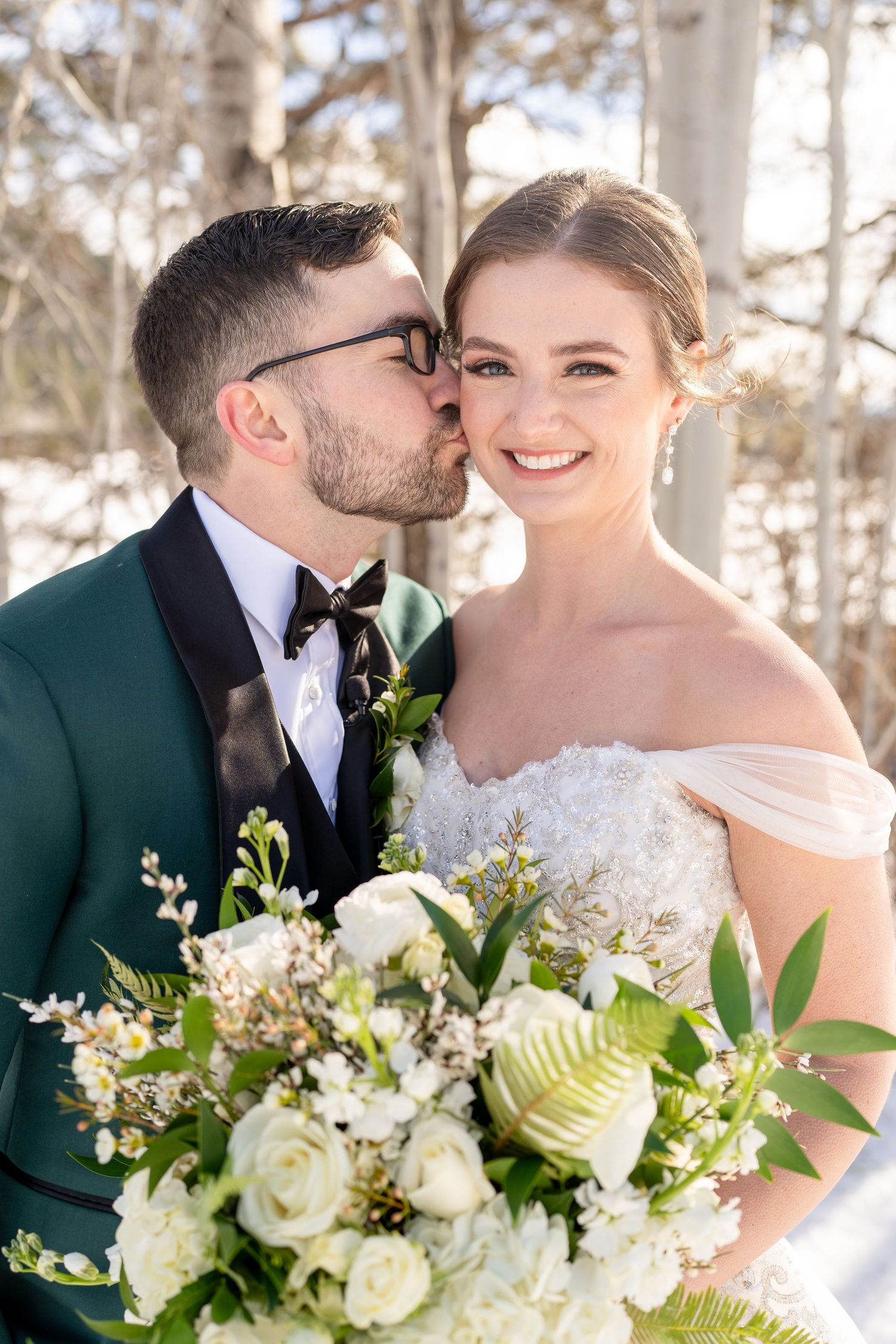 A romantic wedding portrait featuring a bouquet of white roses and greenery.