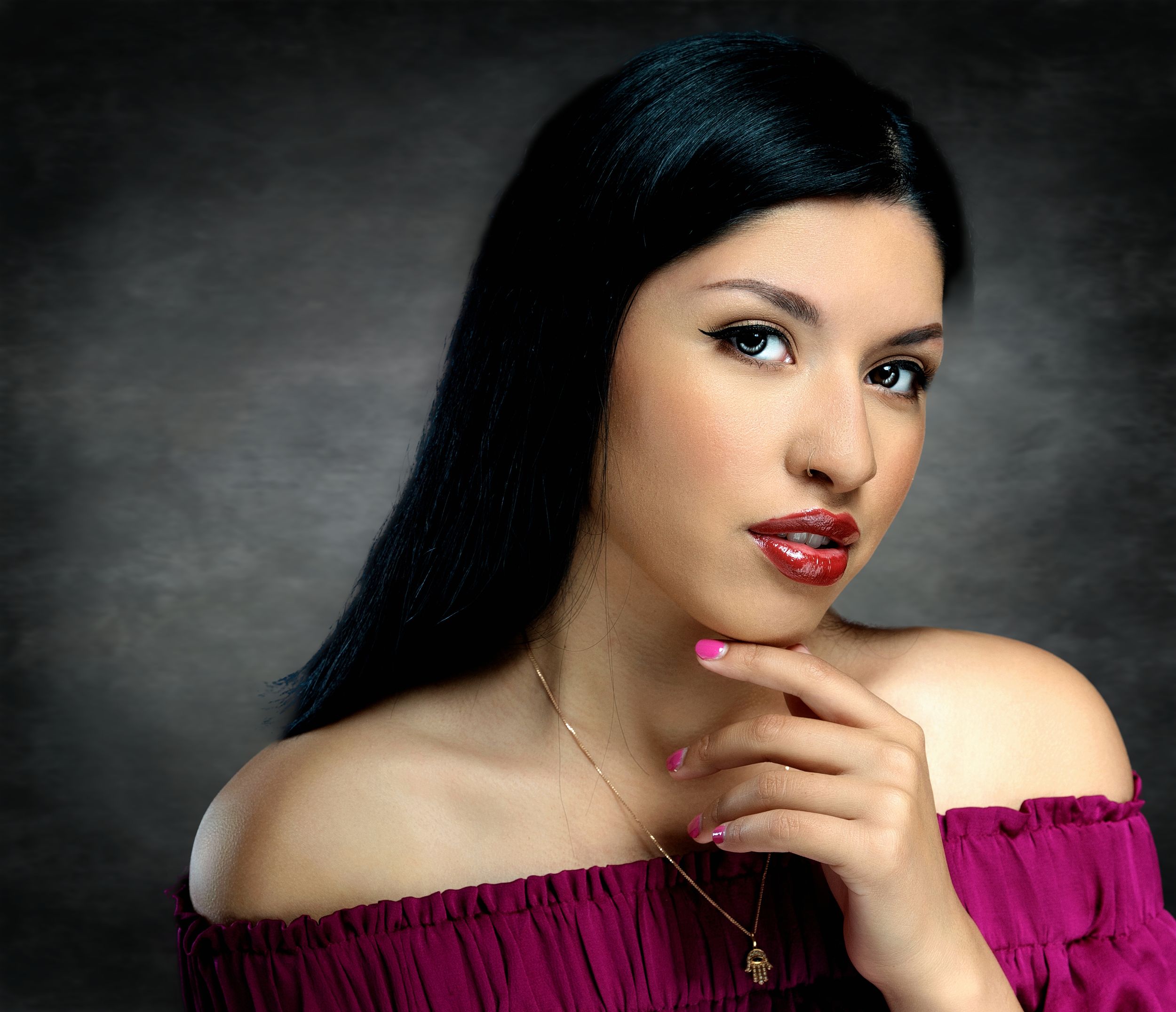 Glamour portrait featuring burgundy off-shoulder top and dramatic makeup.