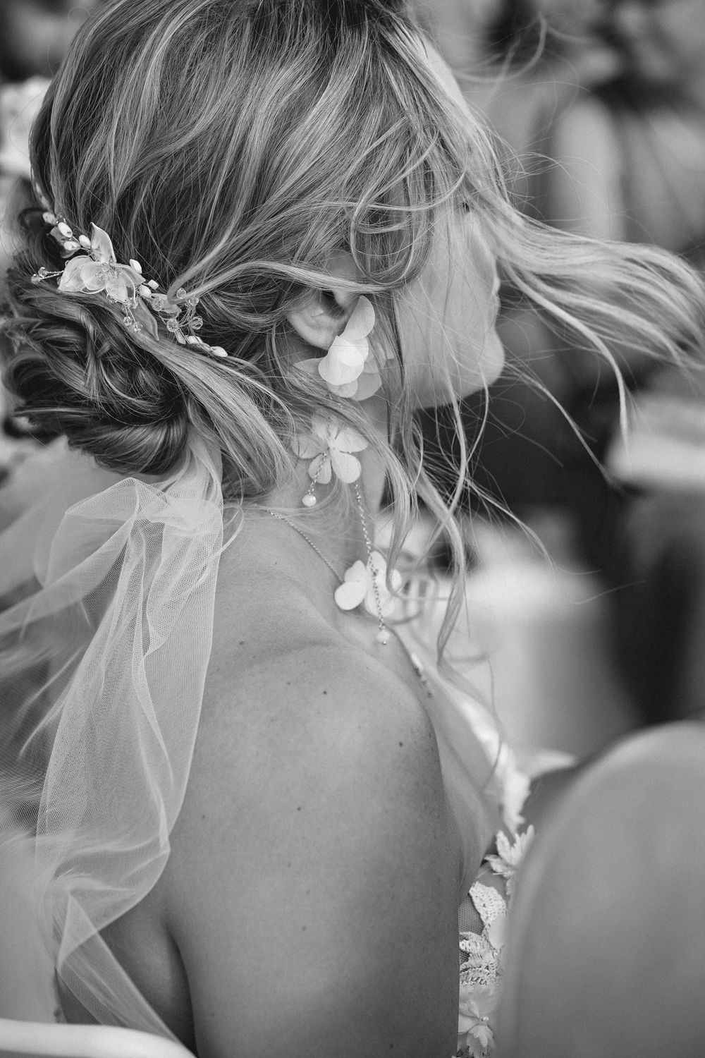 Close-up black and white photo showing delicate bridal hairstyle with braids, veil, and pearl hair accessories.