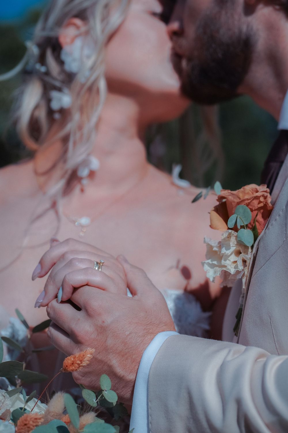 A romantic wedding moment captured with intertwined hands and delicate floral details against a soft blurred background.