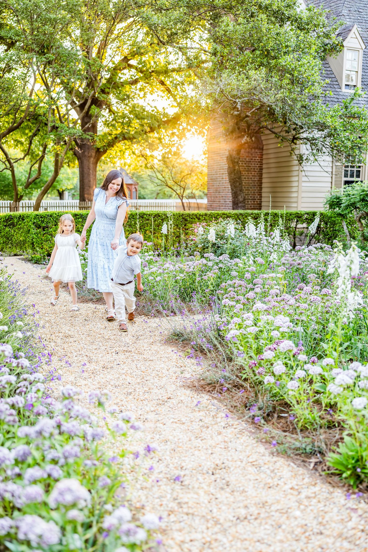 Photography of a family with children and a golden retriever dog posed in a flower filled garden in Colonial Williamsburg, Virginia.