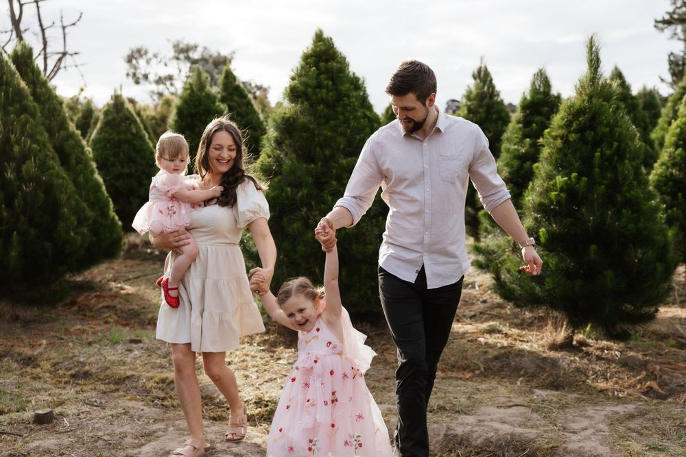 Family bonding during a casual outdoor photoshoot among evergreen trees.