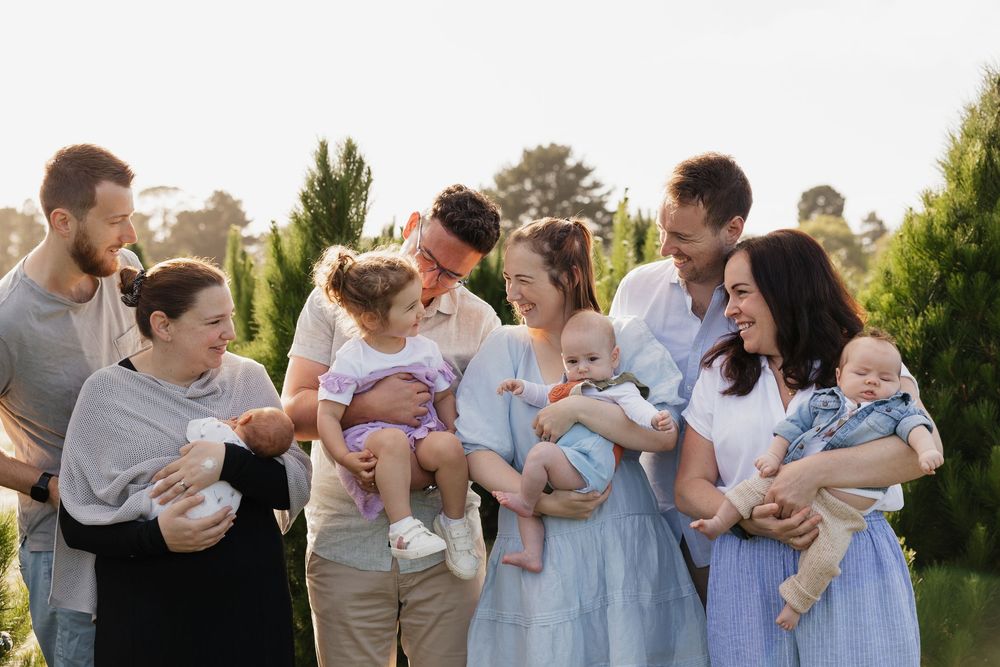 Extended family gathering outdoors wearing coordinated blue and white outfits at Christmas tree farm.