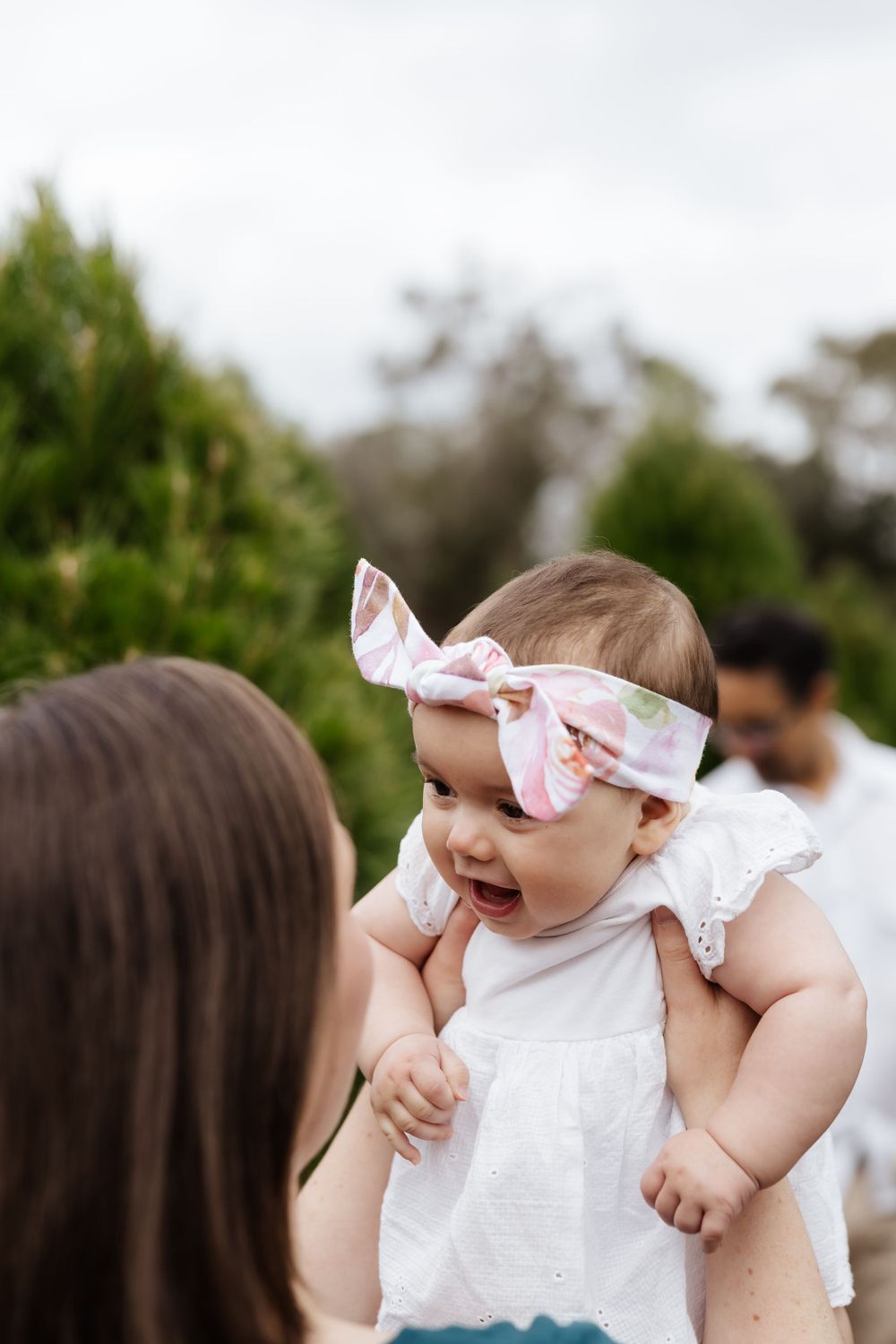 Sweet moment between parent and baby wearing white at an outdoor photo session.