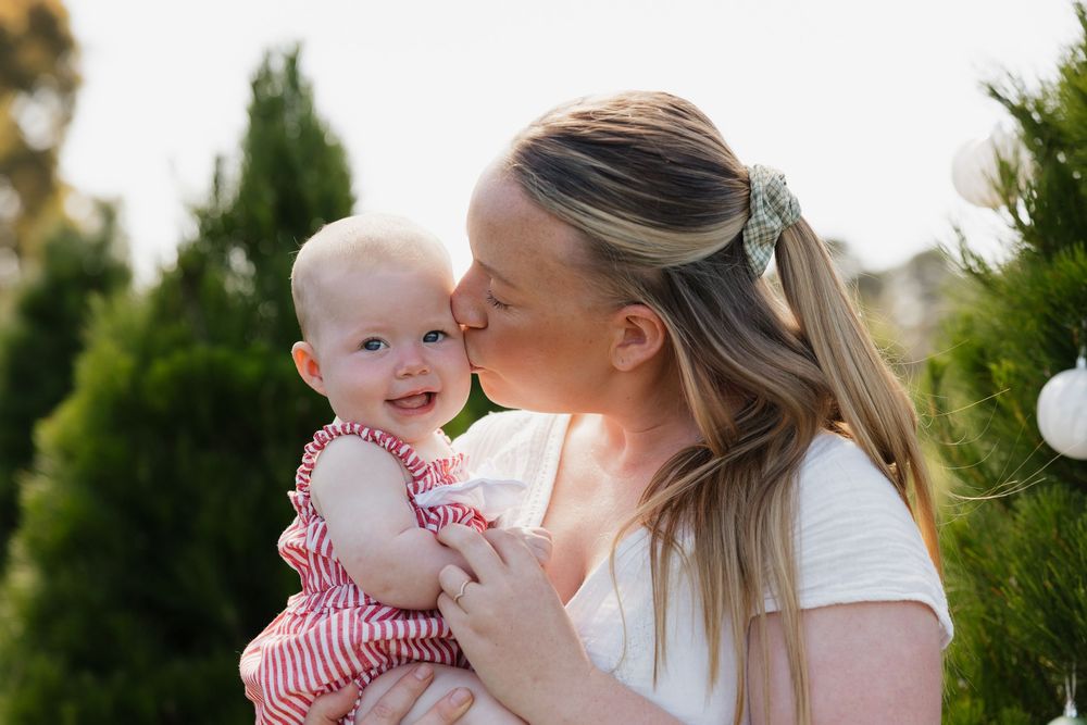 Tender family moments captured outdoors against a backdrop of evergreen trees at Christmas tree farm.