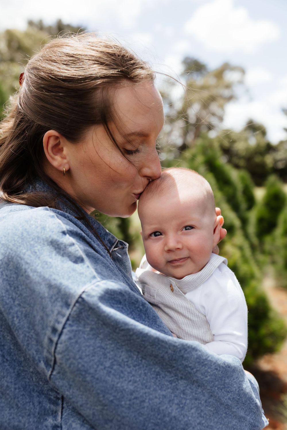 Sweet close-up moments captured between parent and baby outdoors at Christmas tree farm.
