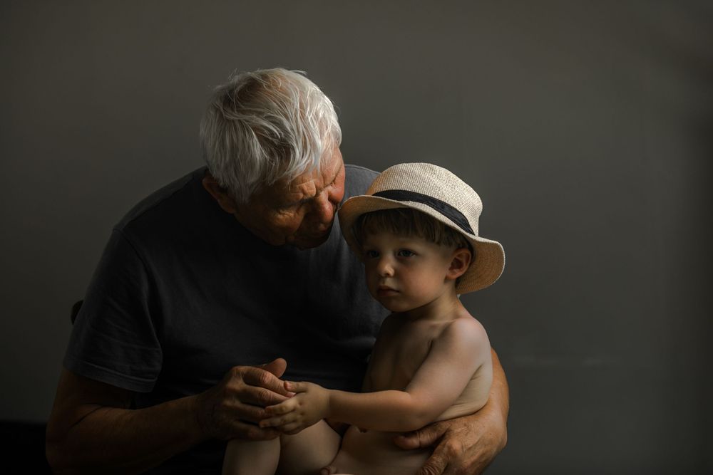 Intimate family moment captured in shadowy dramatic lighting.