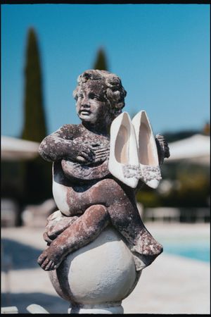 Shoes balanced on a cherub statue at an Italian destination wedding in Tuscany.