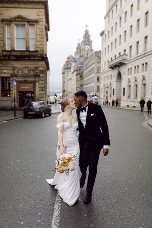 A couple in wedding attire walks down a street in Liverpool at their wedding.