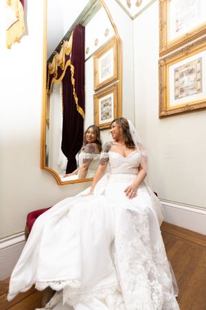 Elegant bridal portrait with ornate gold mirror and vintage decor.