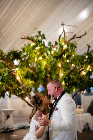 Romantic wedding dance under twinkling lights and greenery-decorated ceiling.