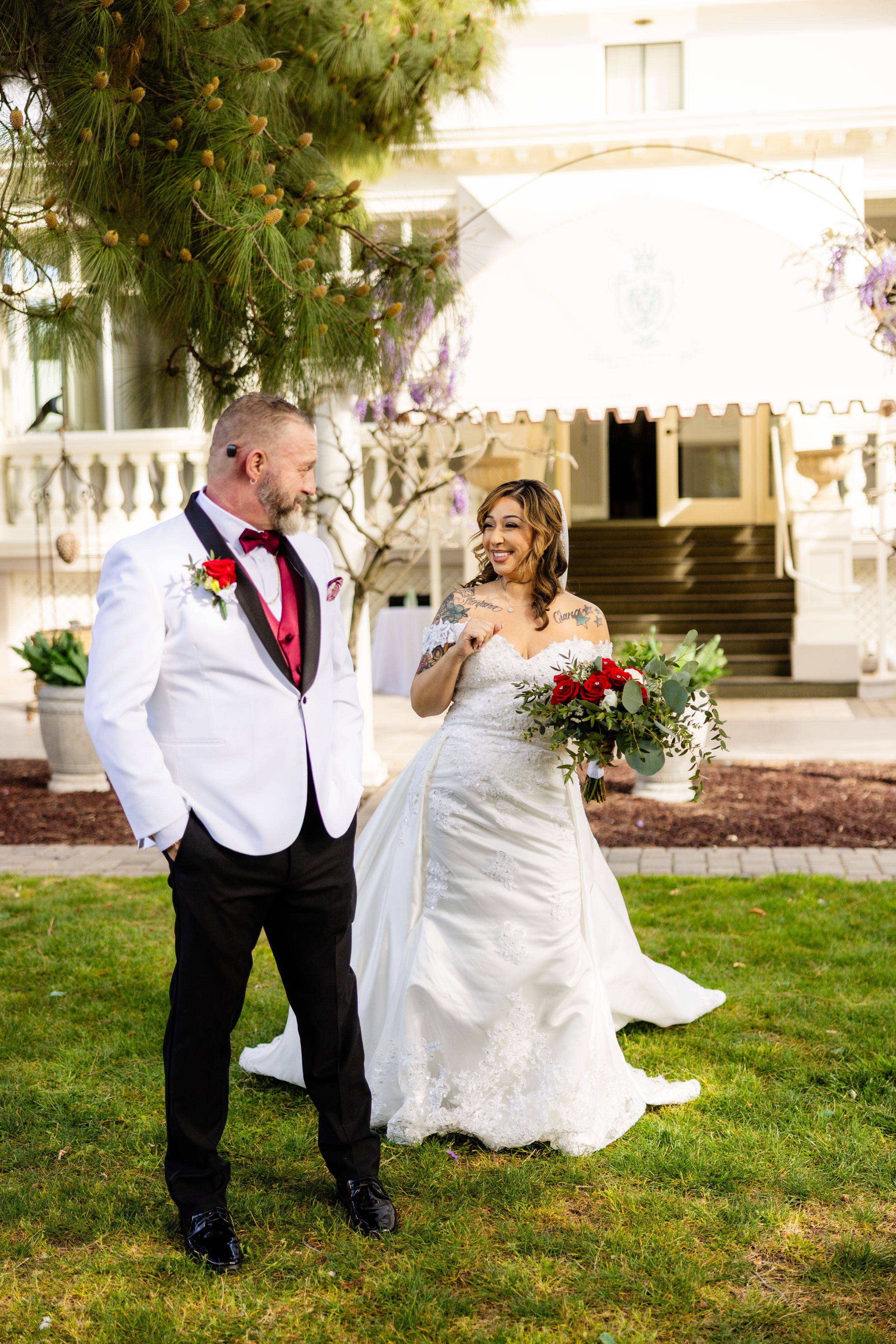 Beautiful wedding couple sharing a joyful moment on manicured lawn of grand estate.