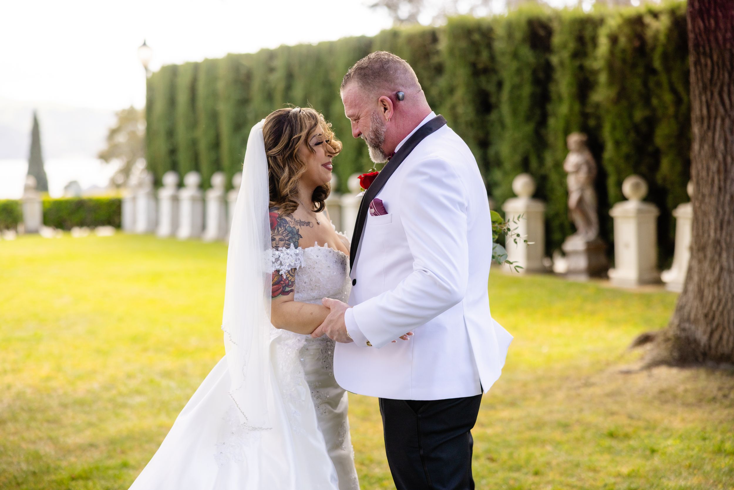 Romantic wedding portrait in outdoor garden setting with white formal attire.