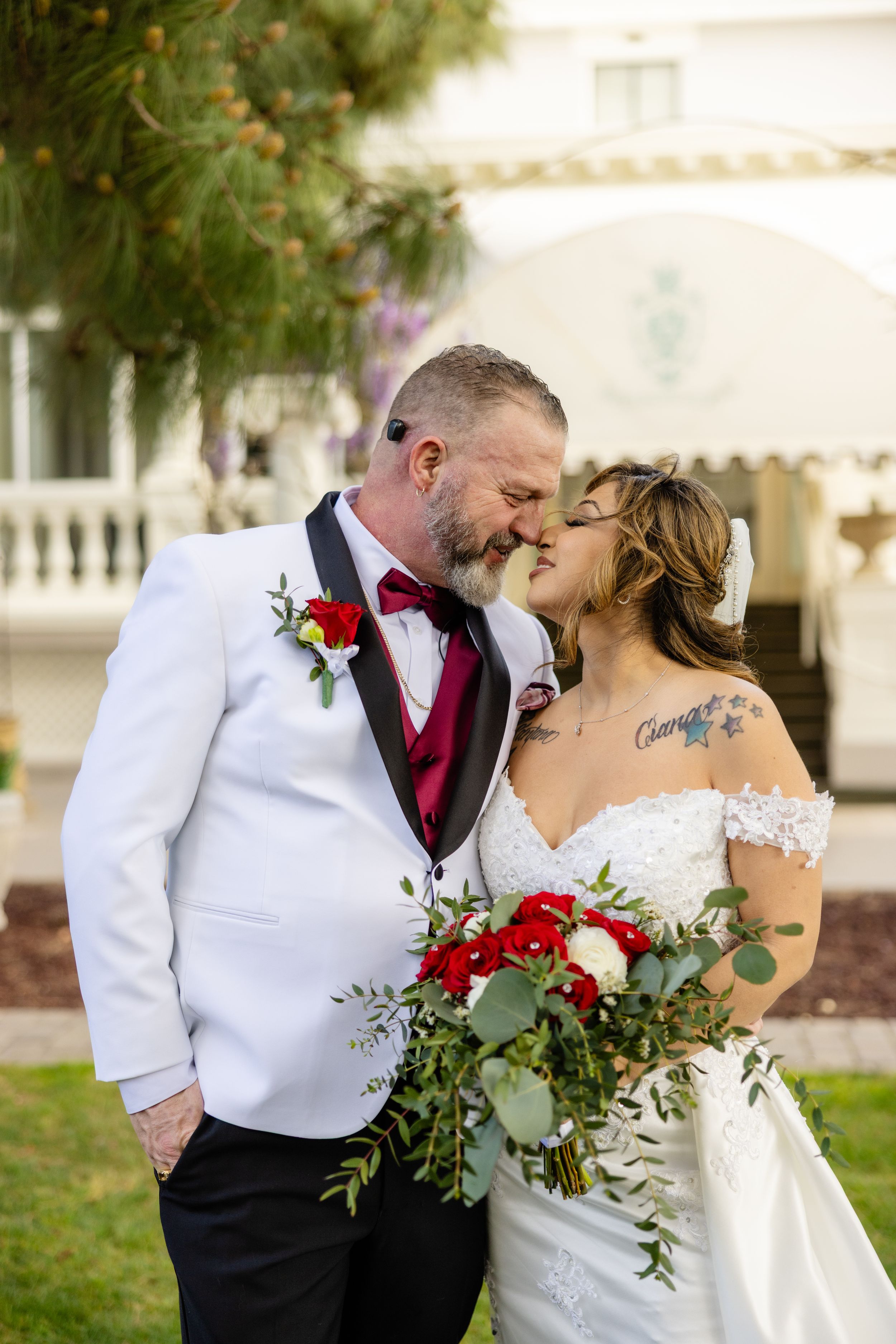 Intimate wedding moment with red and white floral bouquet at elegant venue.