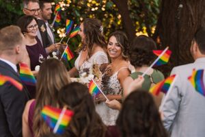 Wedding celebration with guests waving rainbow flags as couple celebrates their special day.