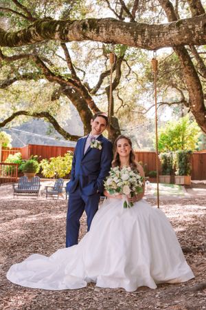 A wedding portrait under a majestic oak tree with a rustic backdrop.