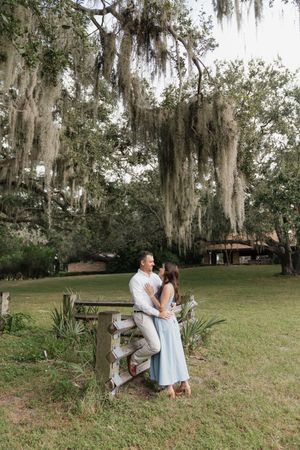 A romantic outdoor photoshoot in a park with Spanish moss hanging from trees in the background.