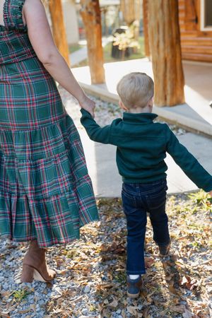 A series of walking steps shown in plaid dress and jeans against fallen autumn leaves on the ground.