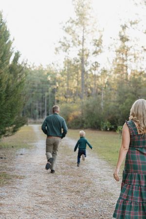 People walking together on a forest trail surrounded by tall pine trees on a sunny autumn afternoon.