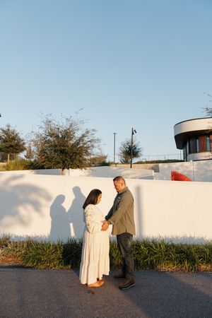 A series of photos showing a couple posing together against a white wall during sunset outdoors.