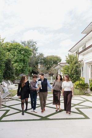 A group of people walking along a modern white pathway with geometric patterns outside a building on a sunny day.
