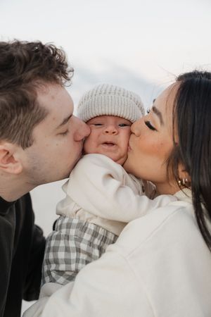 A loving family moment captured in a series of tender kisses on a bright day.