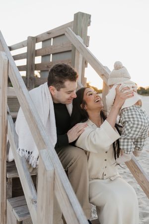 A romantic couple shares tender moments in a sequence of photos on a white wooden deck at sunset.