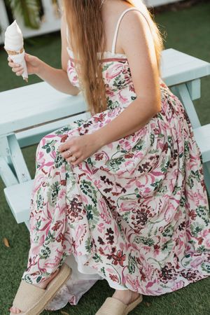 Floral dress details shown in close-up shots on grass, featuring pink and white pattern.