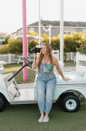 Four lifestyle photos showing someone in overalls sitting beside a vintage white car on green grass.
