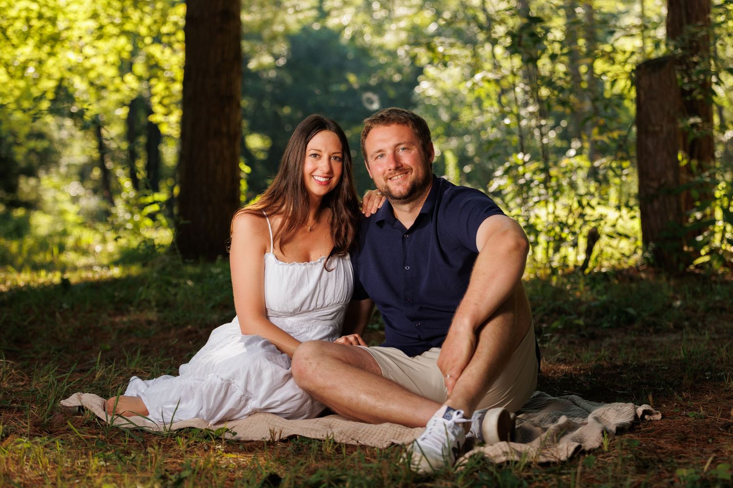 A family smiling at each other during a sunset photo session full of warm light and flare.