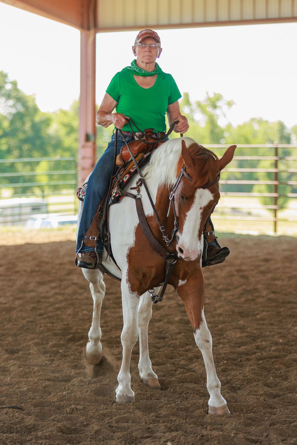 Woman displaying her paint horse's vertical flexion abilities in a covered arena in Missouri.
