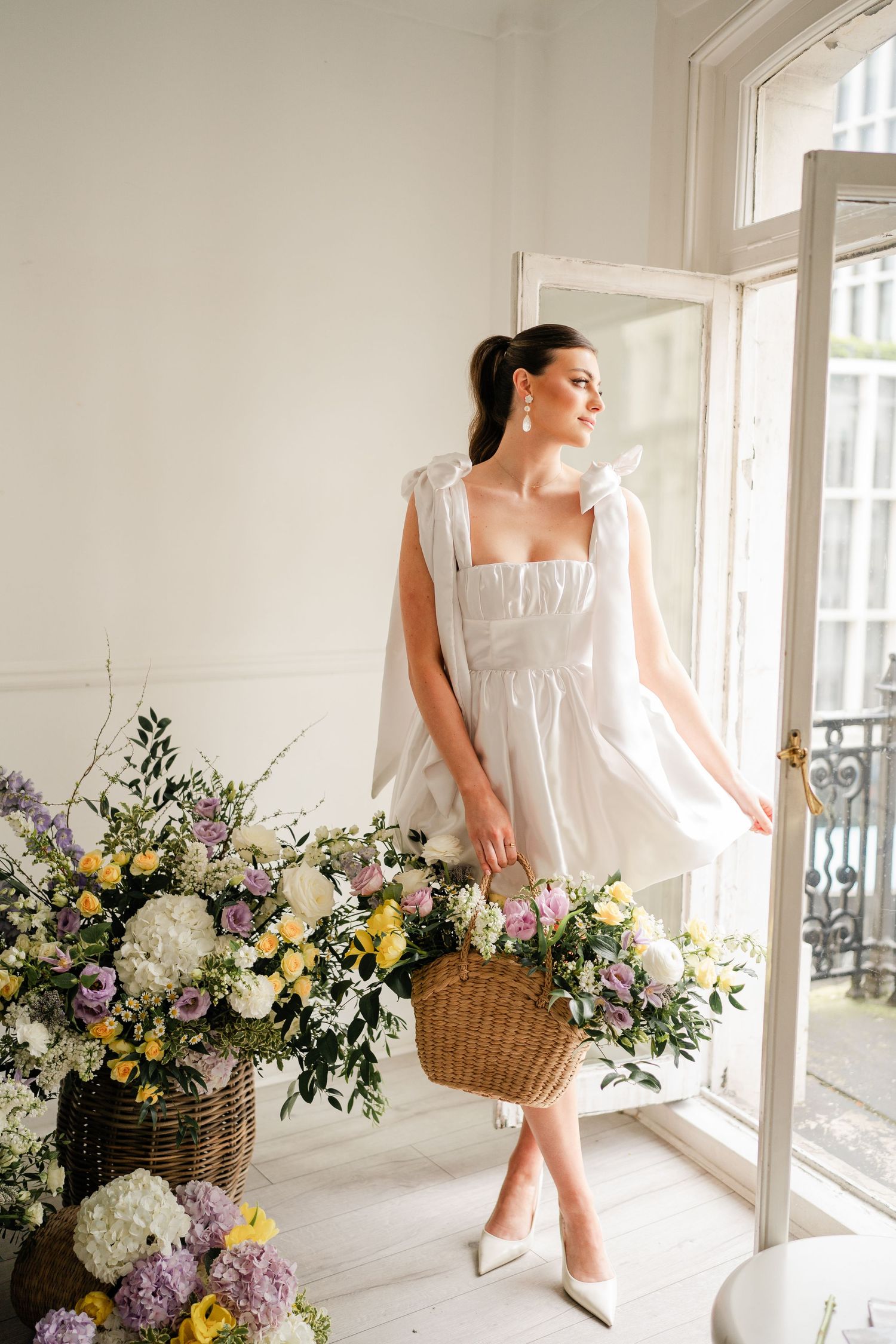Sun-lit bridal scene with wicker basket and colorful spring flower arrangements.