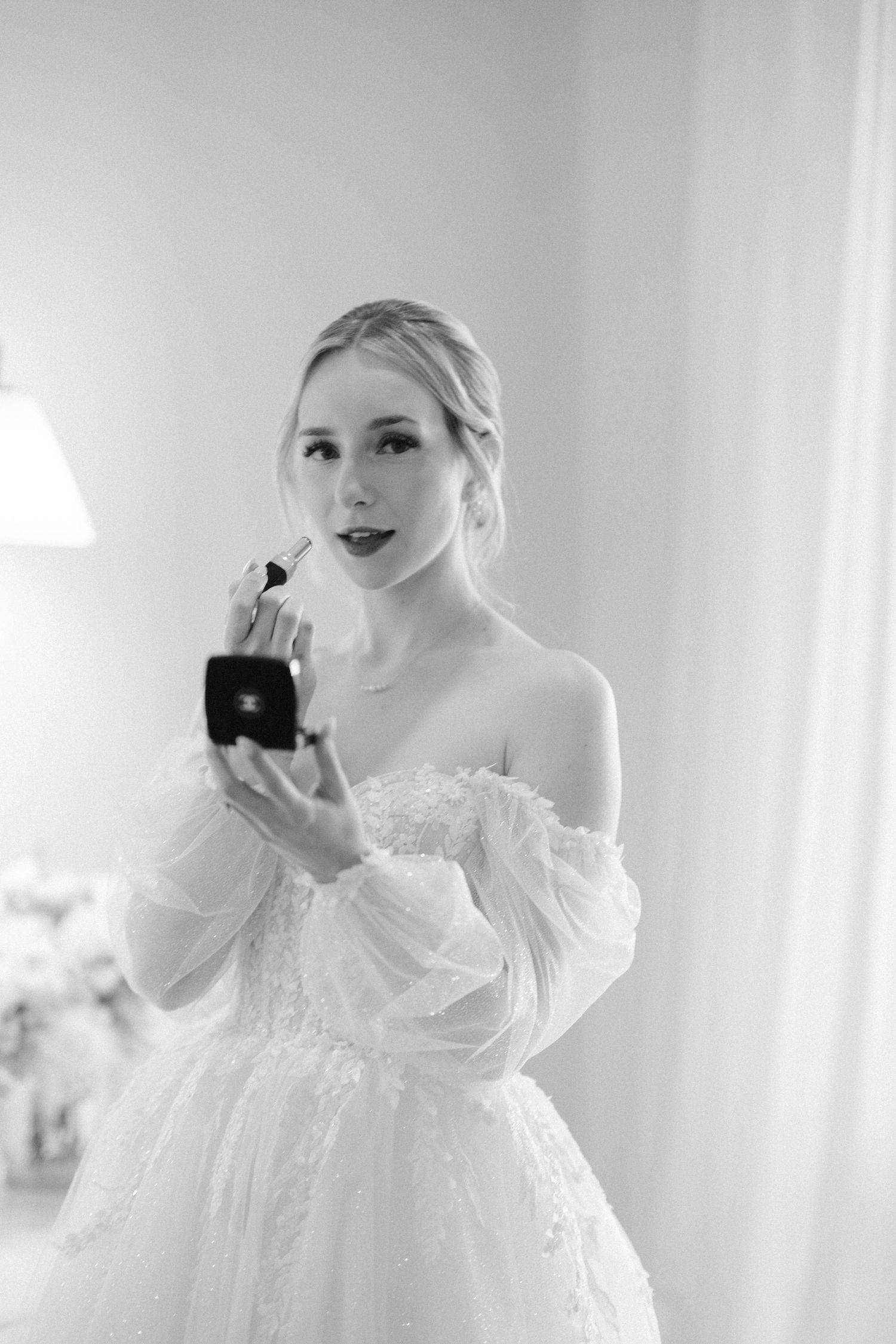 A classic bridal portrait showing an elegant off-shoulder wedding gown and perfume bottle.
