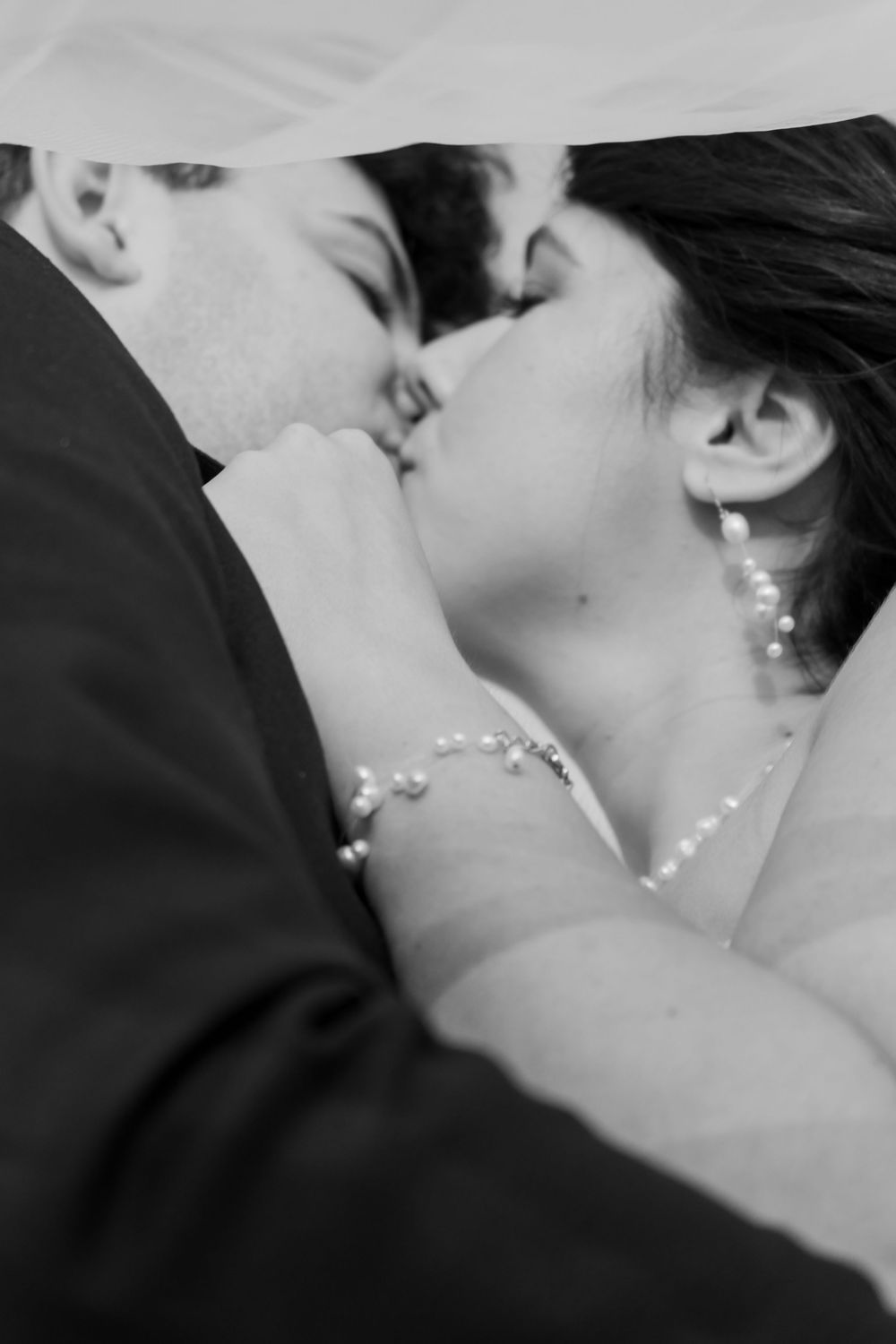 Romantic black and white close-up photo of a couple sharing an intimate kiss on their wedding day.