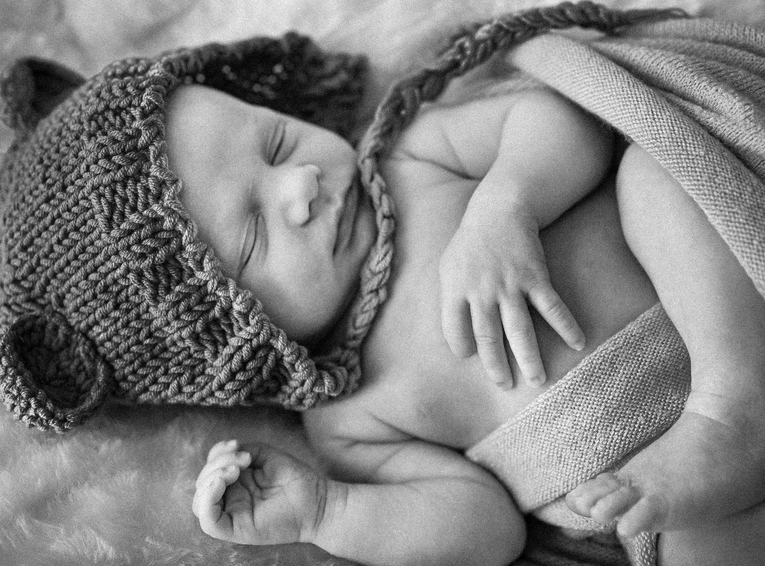 Black and white photographs showing a sleeping baby in knitted clothing.