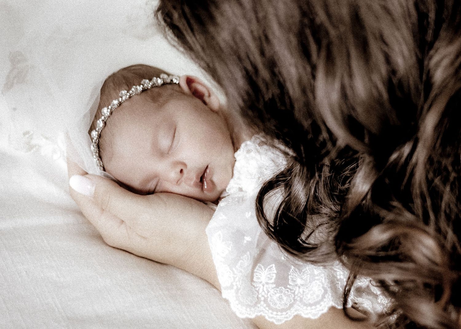 A peaceful black and white portrait of someone sleeping with long dark hair spread across white bedding.
