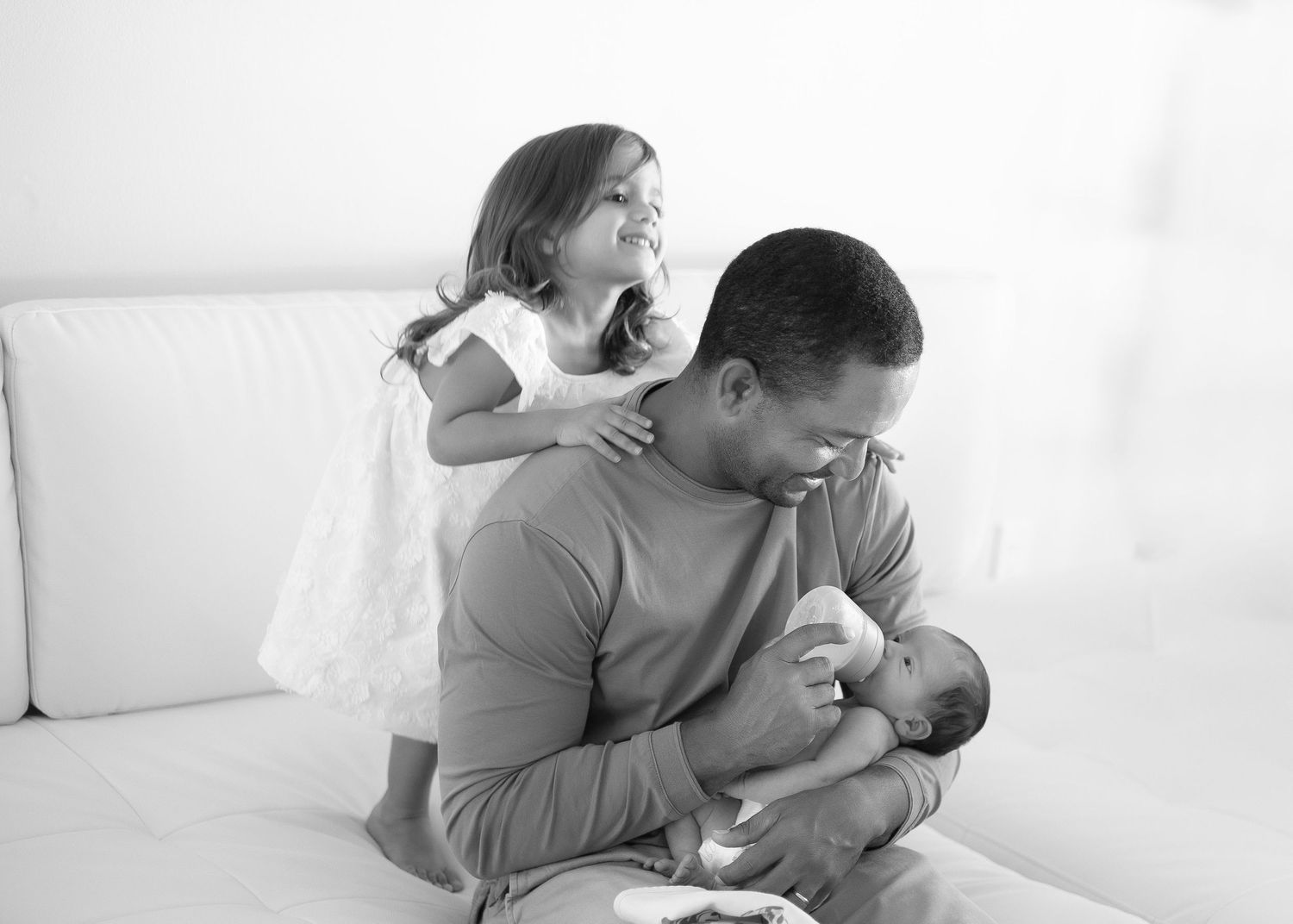 Parent lovingly holds and snuggles with newborn baby in tender black and white portrait series.