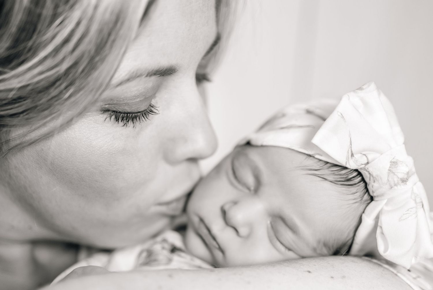 A black and white image showing tender moments between a mama and baby in close-up shot.