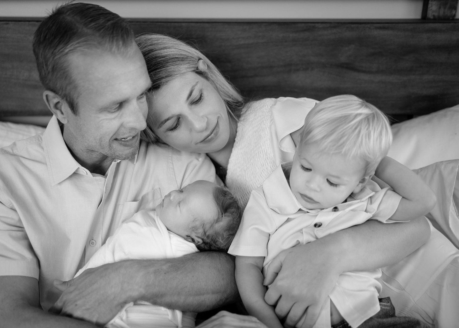 A heartwarming black and white photo series showing tender newborn and toddler family moments in bed. Lifestyle In-home Newborn Photography.
