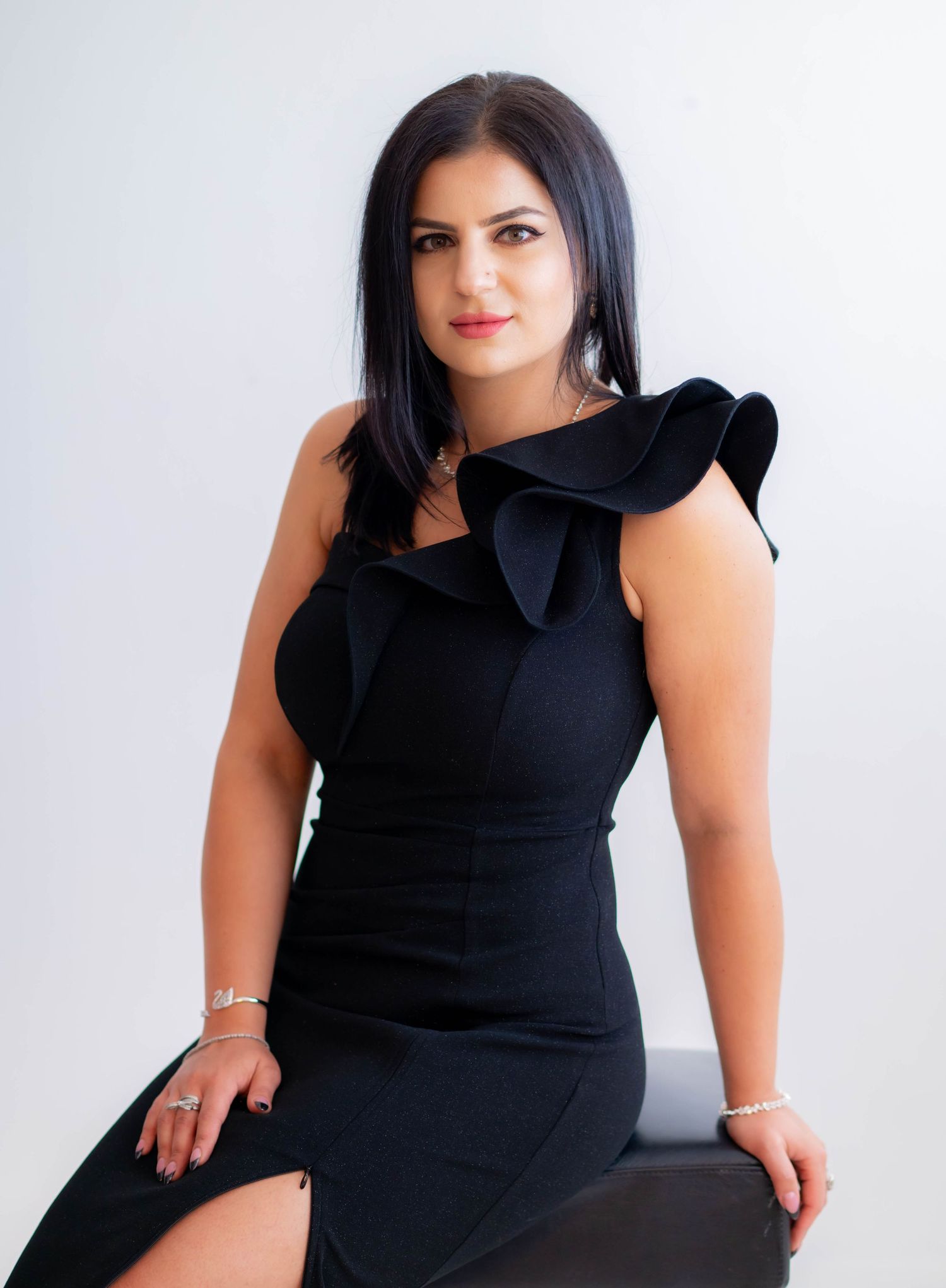 Studio portraits showcasing black dress with ruffle detail in classic poses.