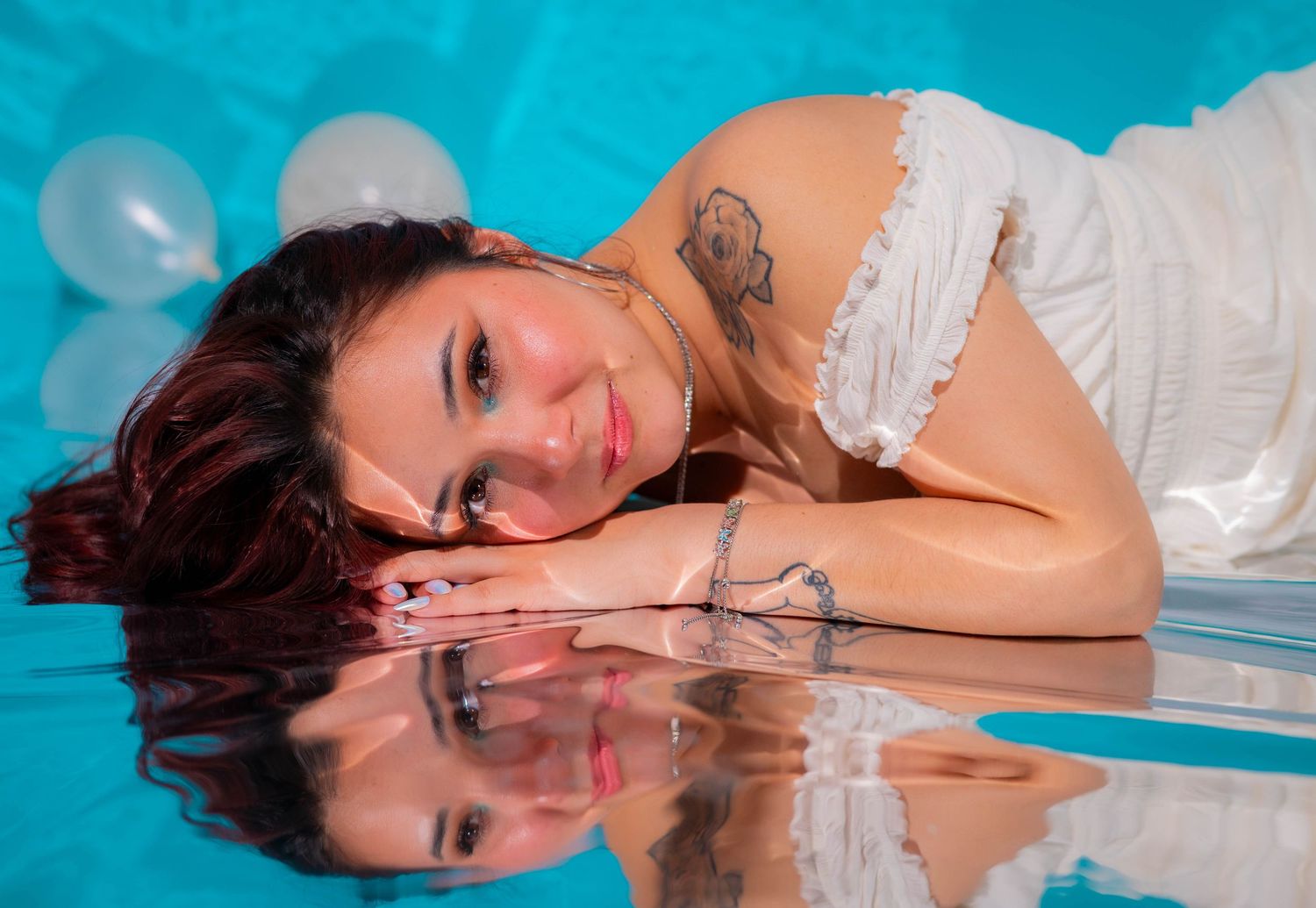 Artistic portrait with reflective surface and white dress against turquoise background.